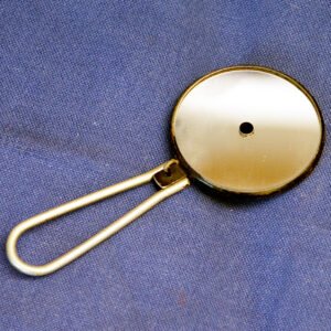 Antique early 1900s foldable pocket ophthalmoscope with circular concave mirror and folding wire handle, used for basic eye examination by general practitioners